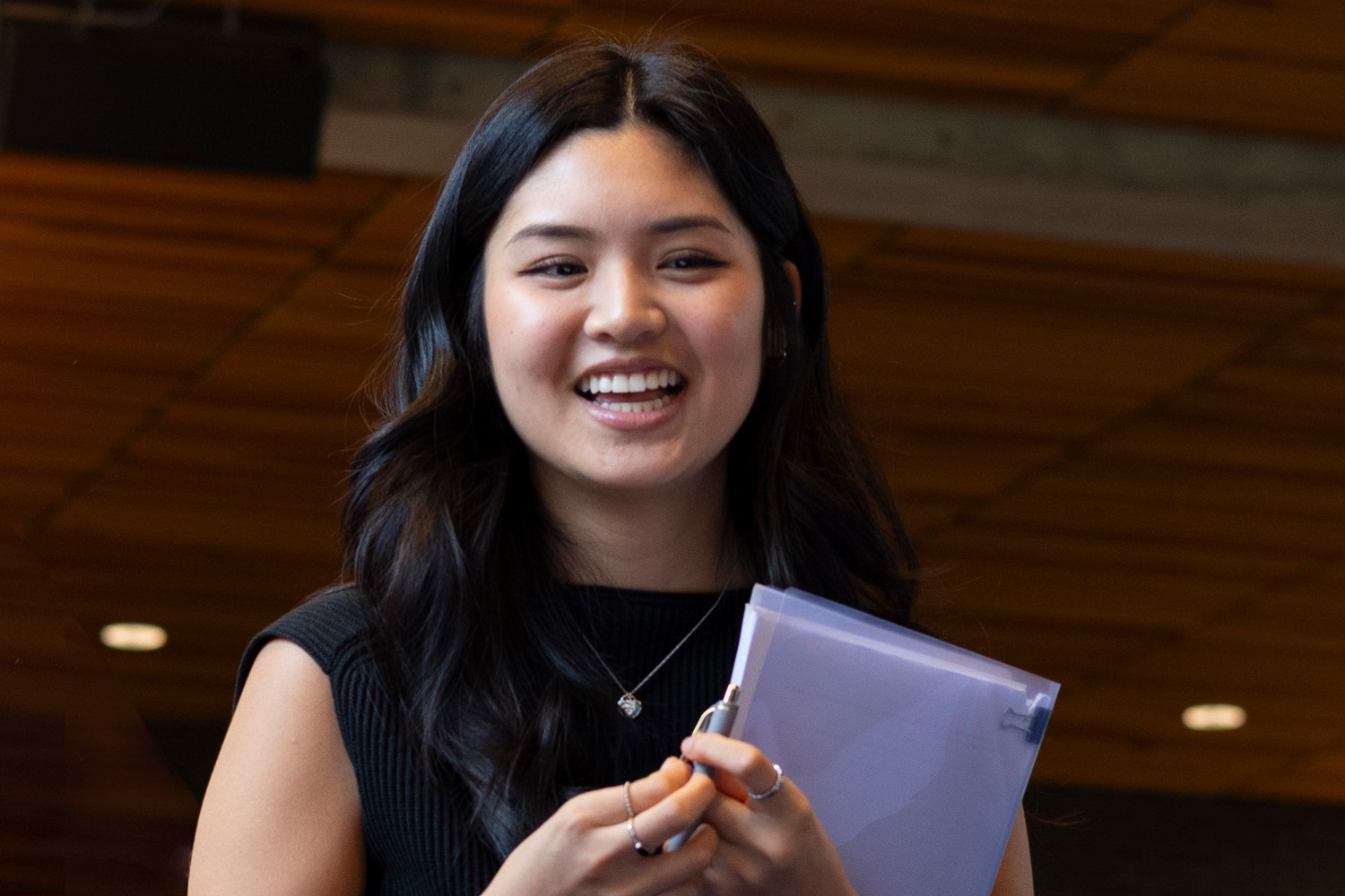 A woman holding a folder, smiling